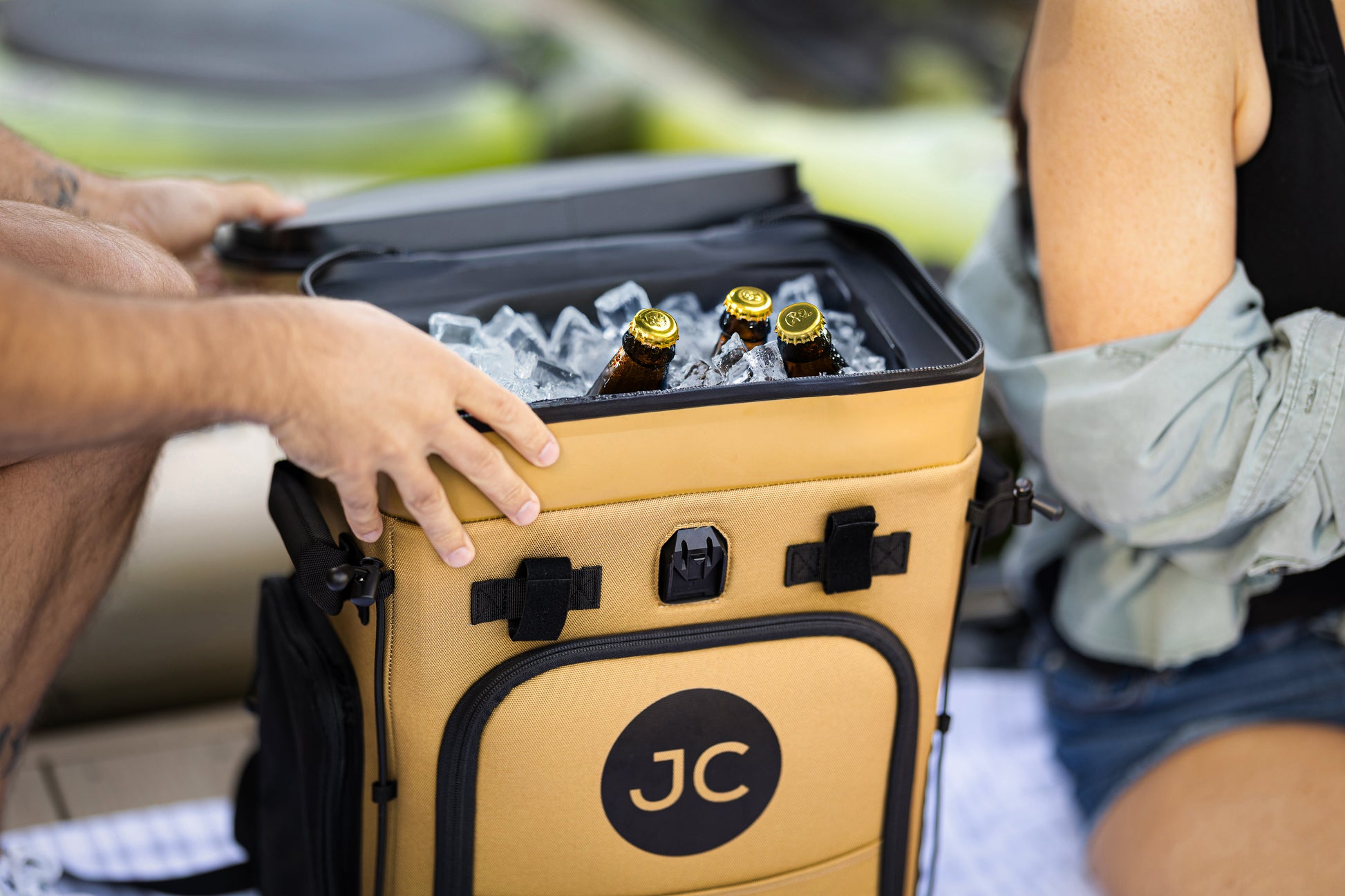 Person opening a yellow JC branded cooler with bottles inside