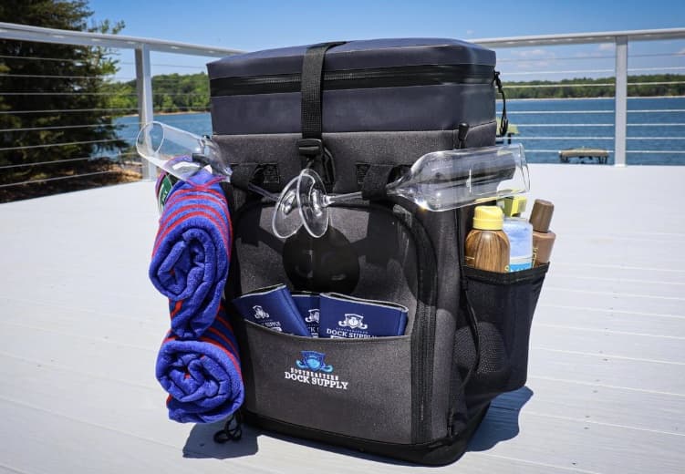 A custom-branded JustinCASE bag on a dock, with can sleeves and two wine glasses beside it