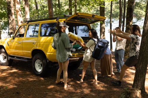 Group of people by a yellow SUV with JustinCASE Convertible Backpack